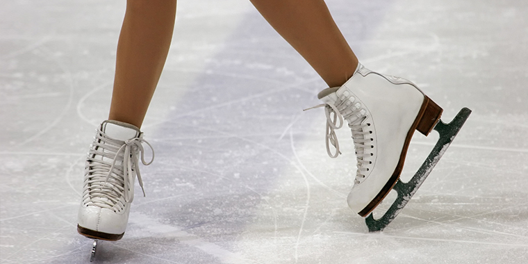 Olympic figure skater poses in ice skates on the ice rink