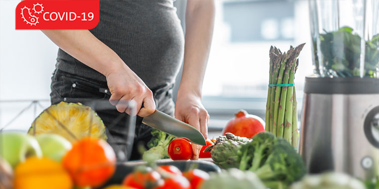 Pregnant woman chopping up vegetables